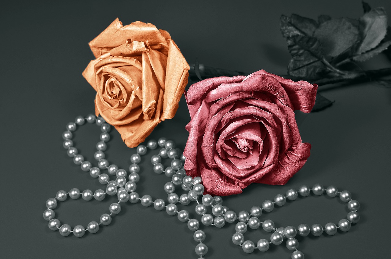 Two roses with a strand of pearls.