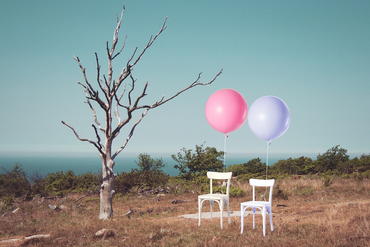 Pink and purple balloons tied to white chairs.