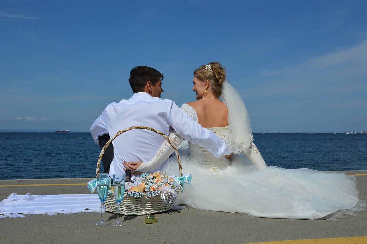 Bride and groom on beach with glasses of champagne.