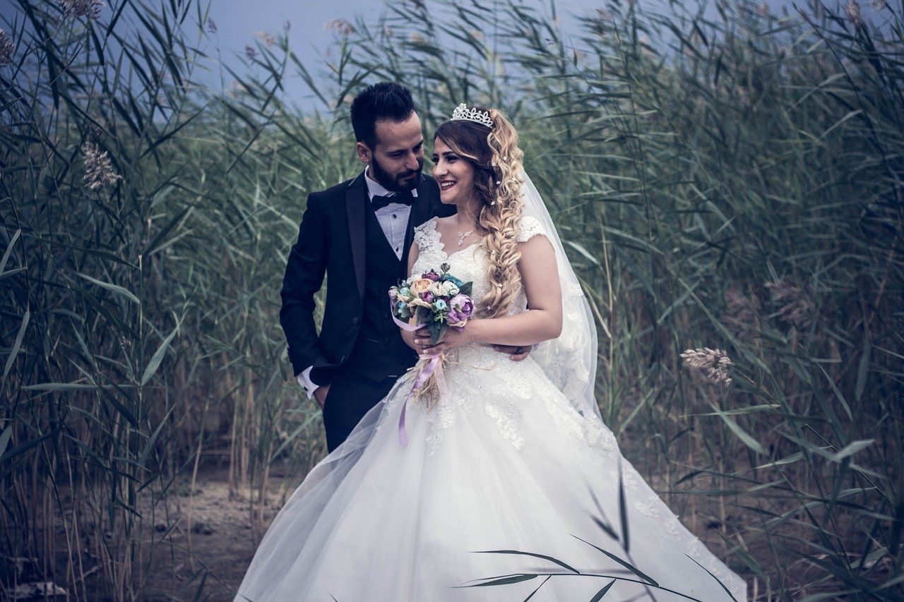 Bride and groom standing in a field.
