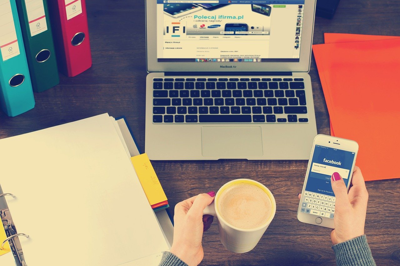 An open laptop and a phone with the Facebook logo on it.