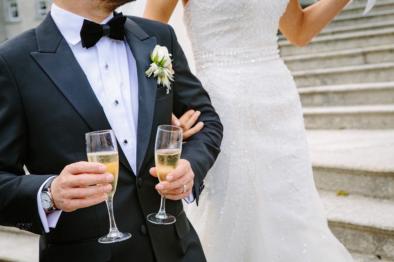 Groom holding two flutes of champagne.
