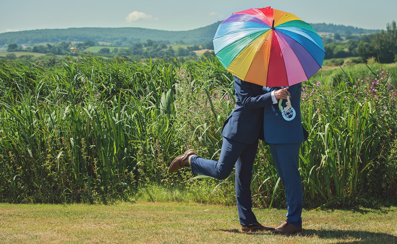 Two grooms with a rainbow umbrella.
